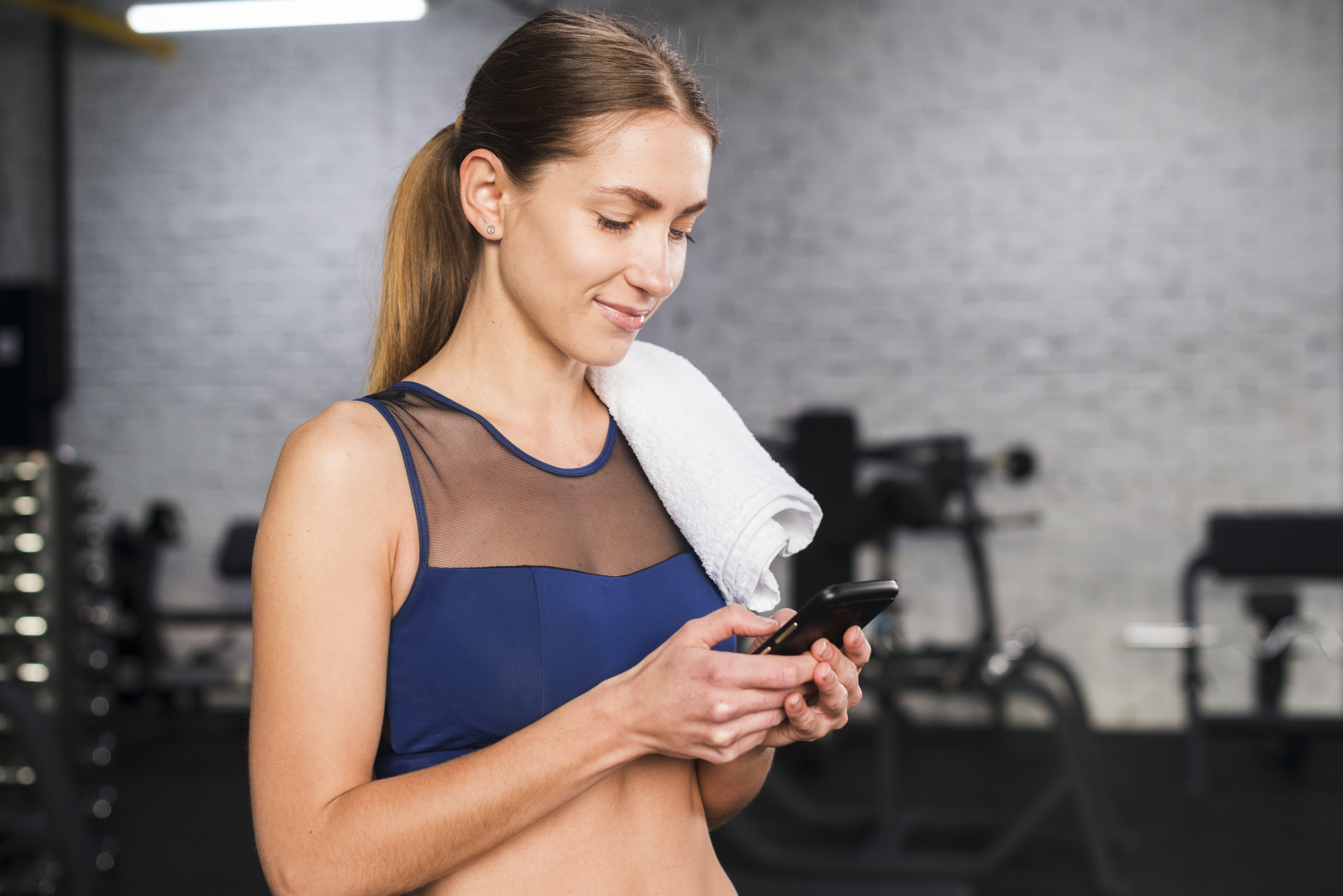 Woman using smartphone fitness technology with QR code integration for balanced wellness tracking